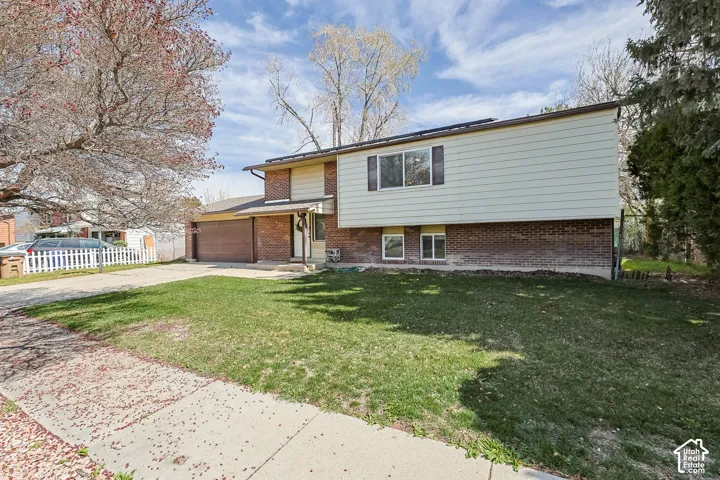 Split-level residence featuring a brick and siding exterior, an attached two-car garage, and a concrete driveway