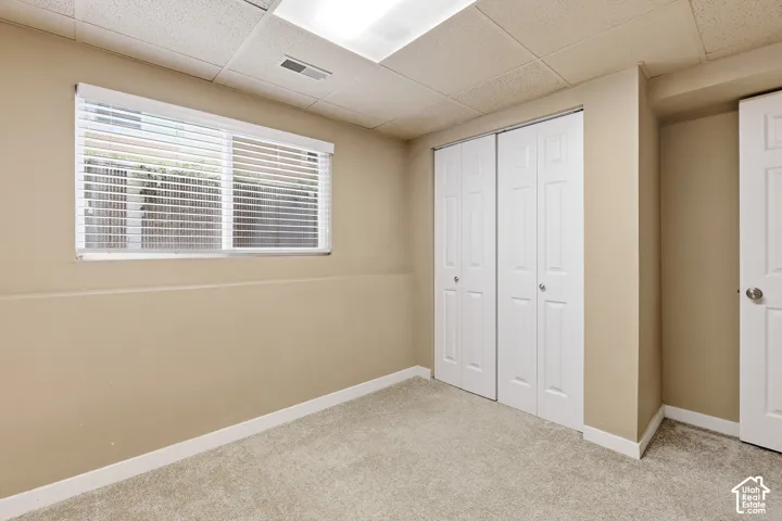 Carpeted room featuring a window with blinds, bi-fold closet doors, and recessed lighting