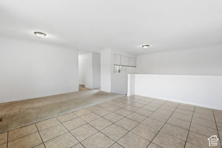 Spacious interior featuring a tiled flooring area, carpeted flooring area, and a half-wall partition