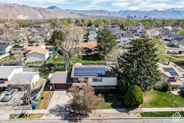 Single-story residence featuring solar panels, an attached garage, and a paved driveway