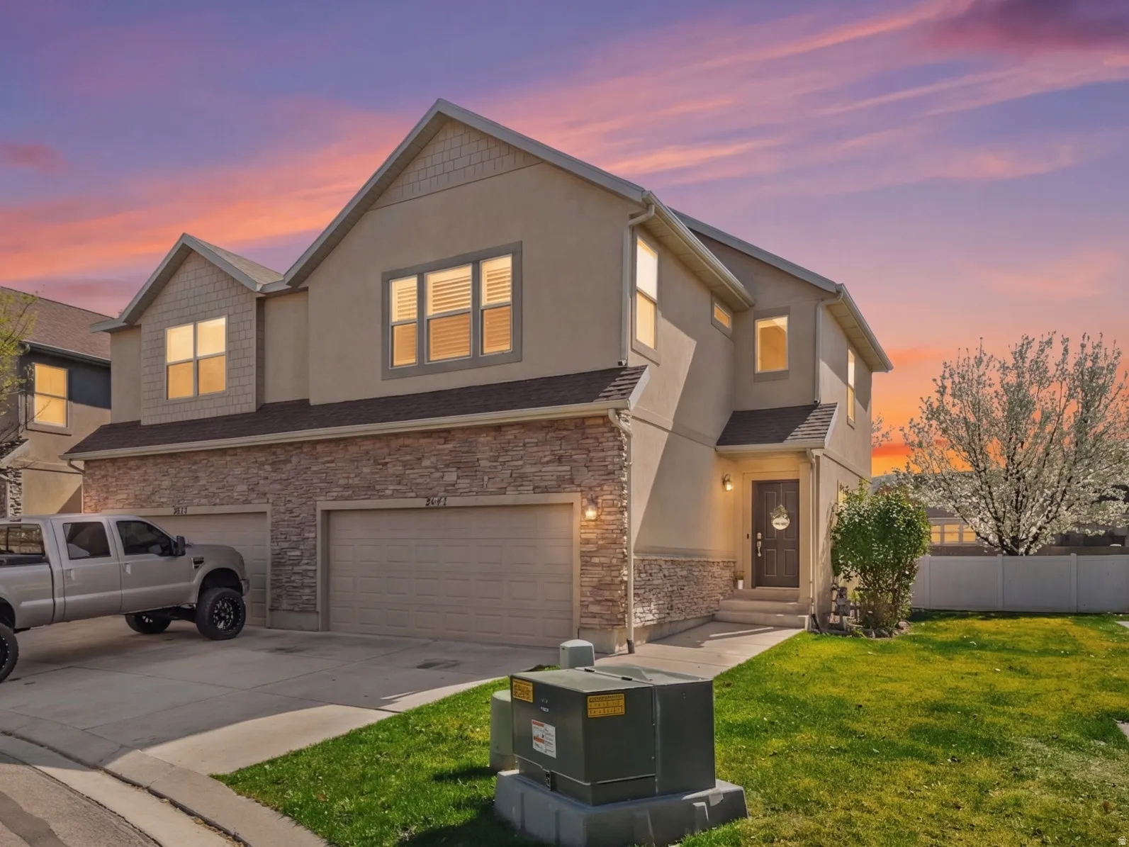 Traditional-style home featuring a garage, driveway, stucco siding, and stone siding