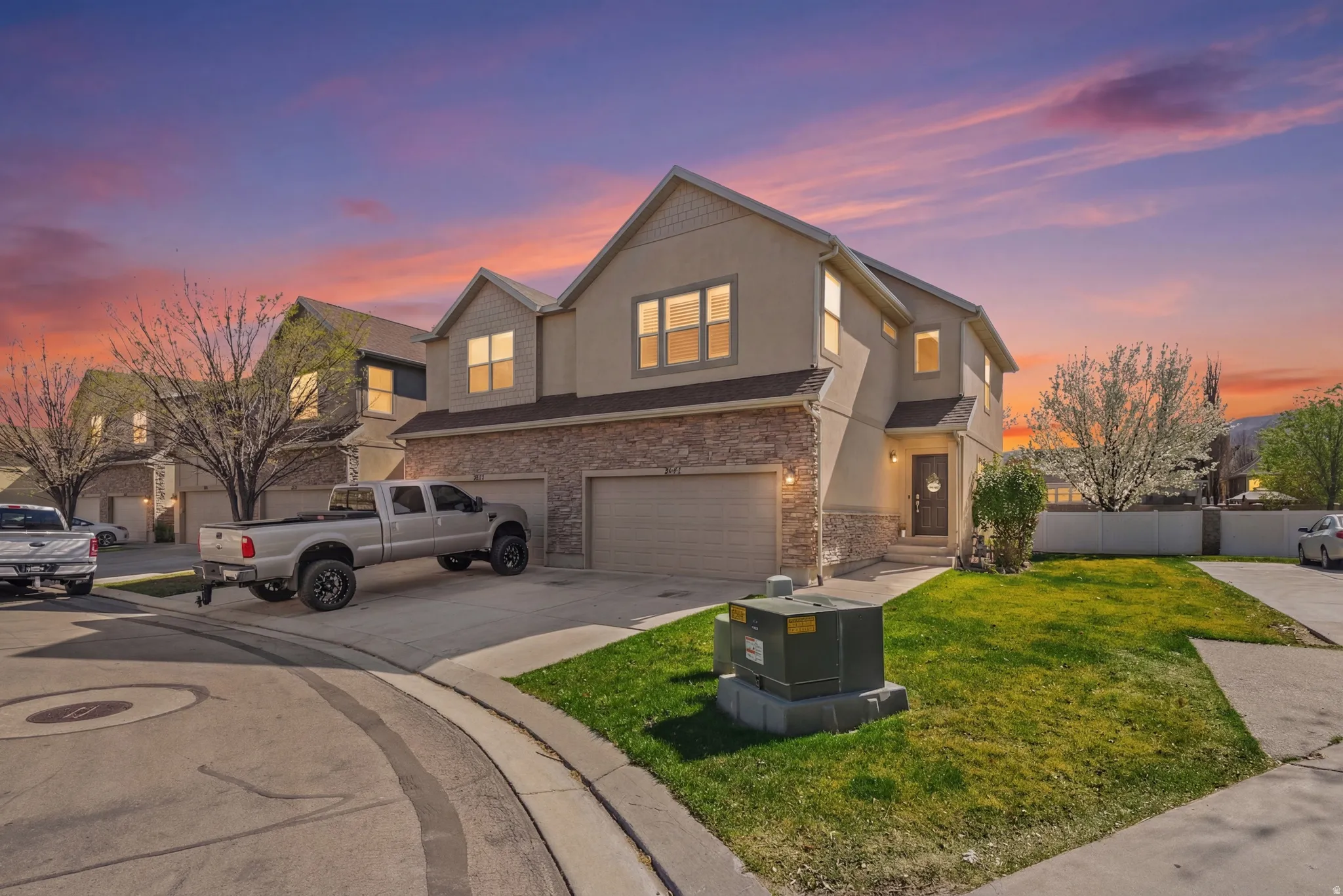 Traditional-style home featuring a garage, driveway, stucco siding, and stone siding