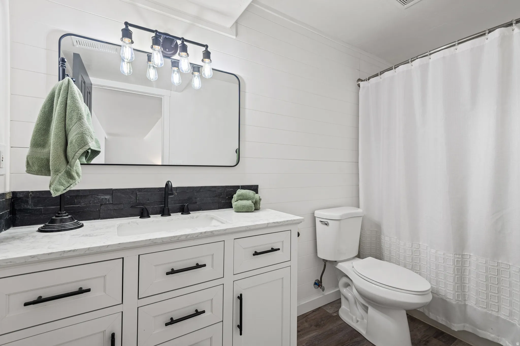 Full bathroom featuring vanity, wooden walls, and dark wood-style floors