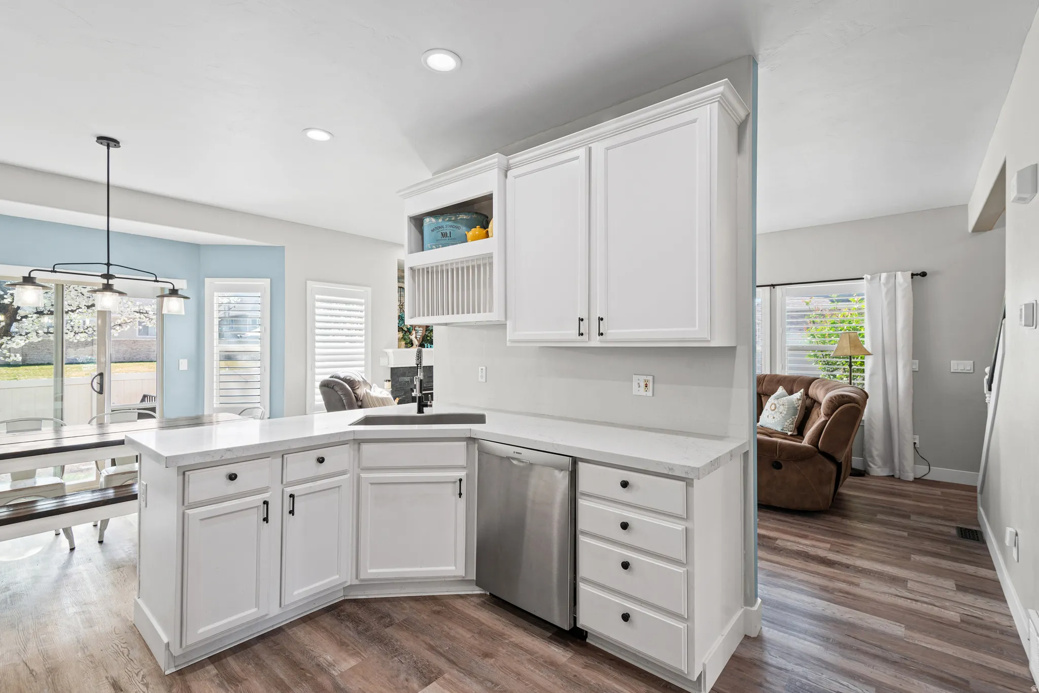 Kitchen featuring a peninsula, white cabinets, stainless steel dishwasher, dark wood-style flooring, and open shelves
