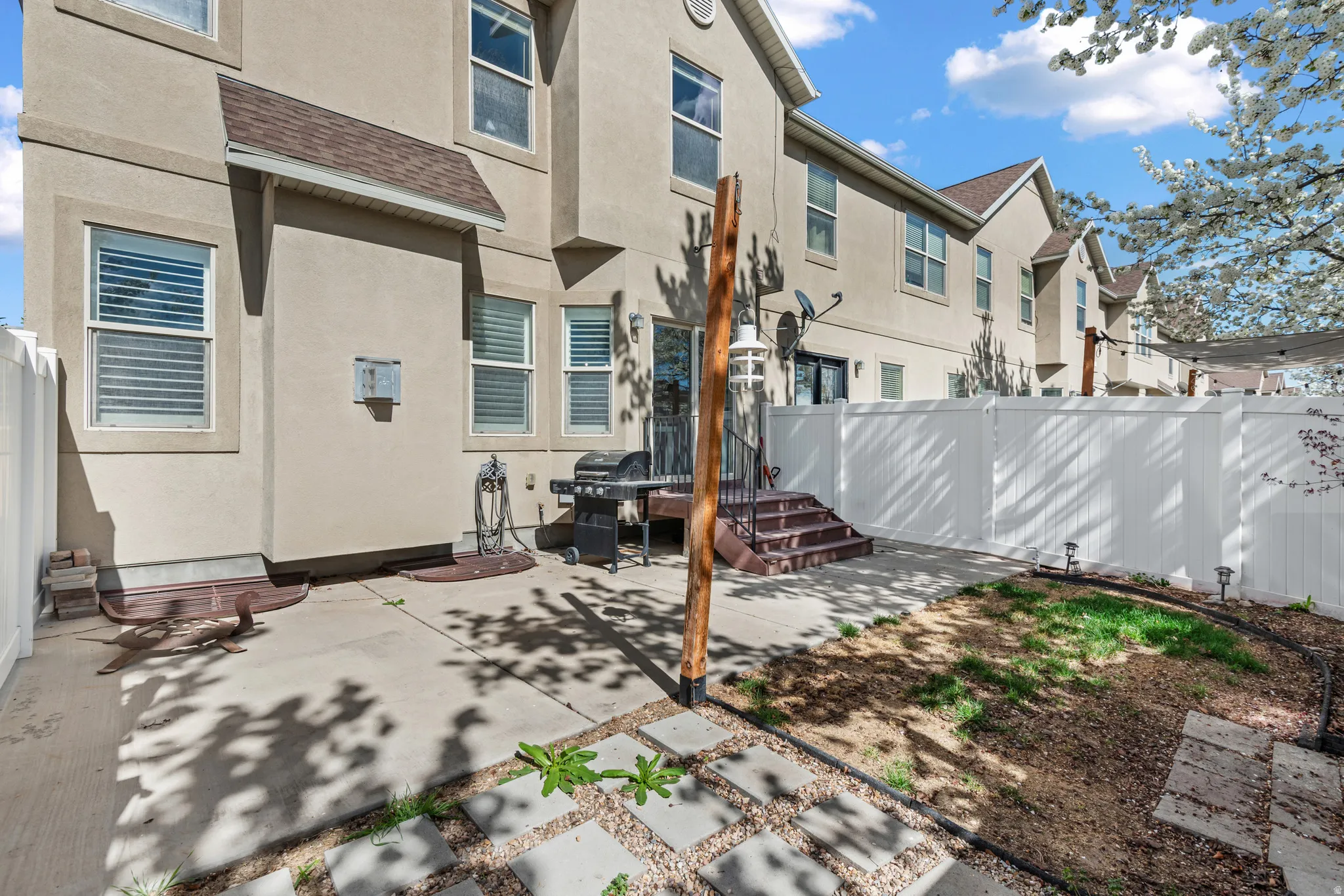 Rear view of house featuring a fenced backyard, roof with shingles, stucco siding, and a patio