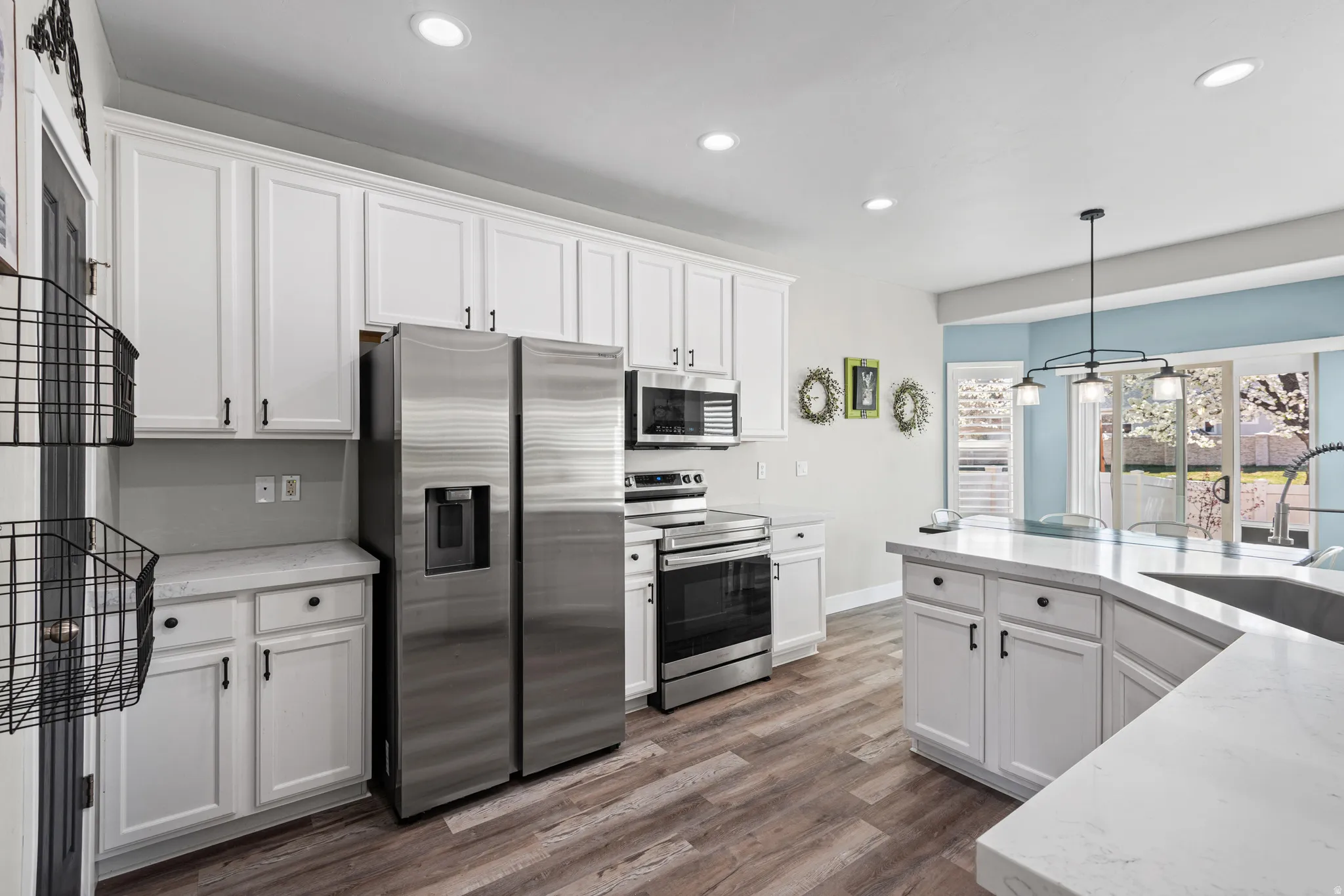Kitchen with stainless steel appliances, white cabinets, dark wood-style floors, and light stone counters