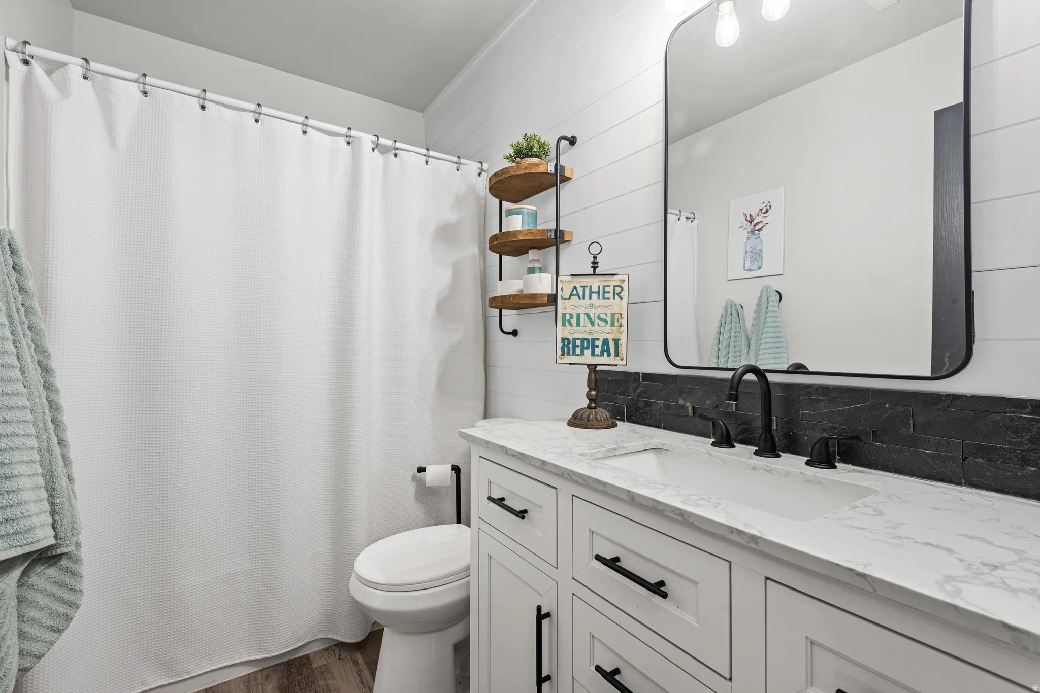 Bathroom featuring vanity, wooden walls, curtained shower, and dark wood-type flooring