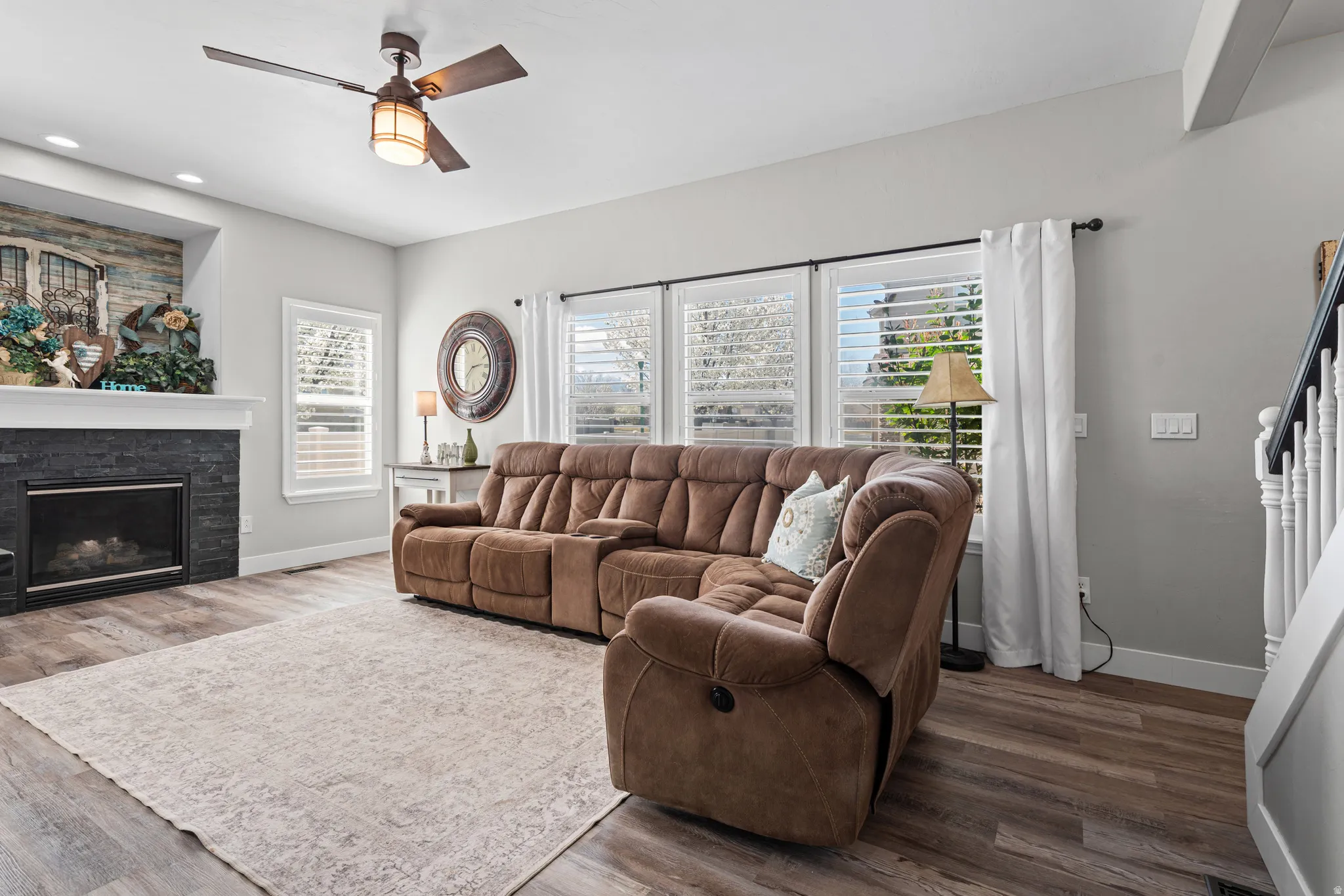 Living area featuring wood finished floors, a ceiling fan, and a fireplace.