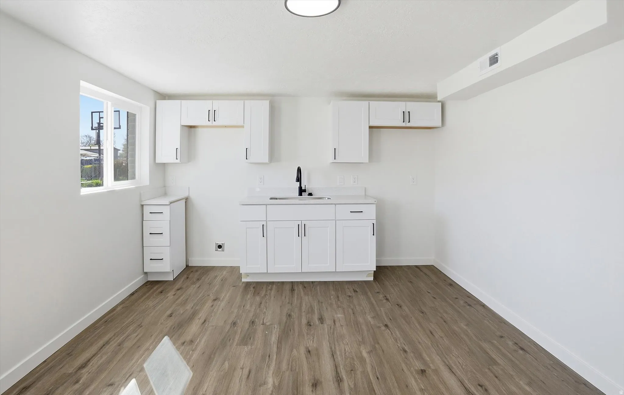 Bar with white cabinetry, light countertops, and light wood finished floors