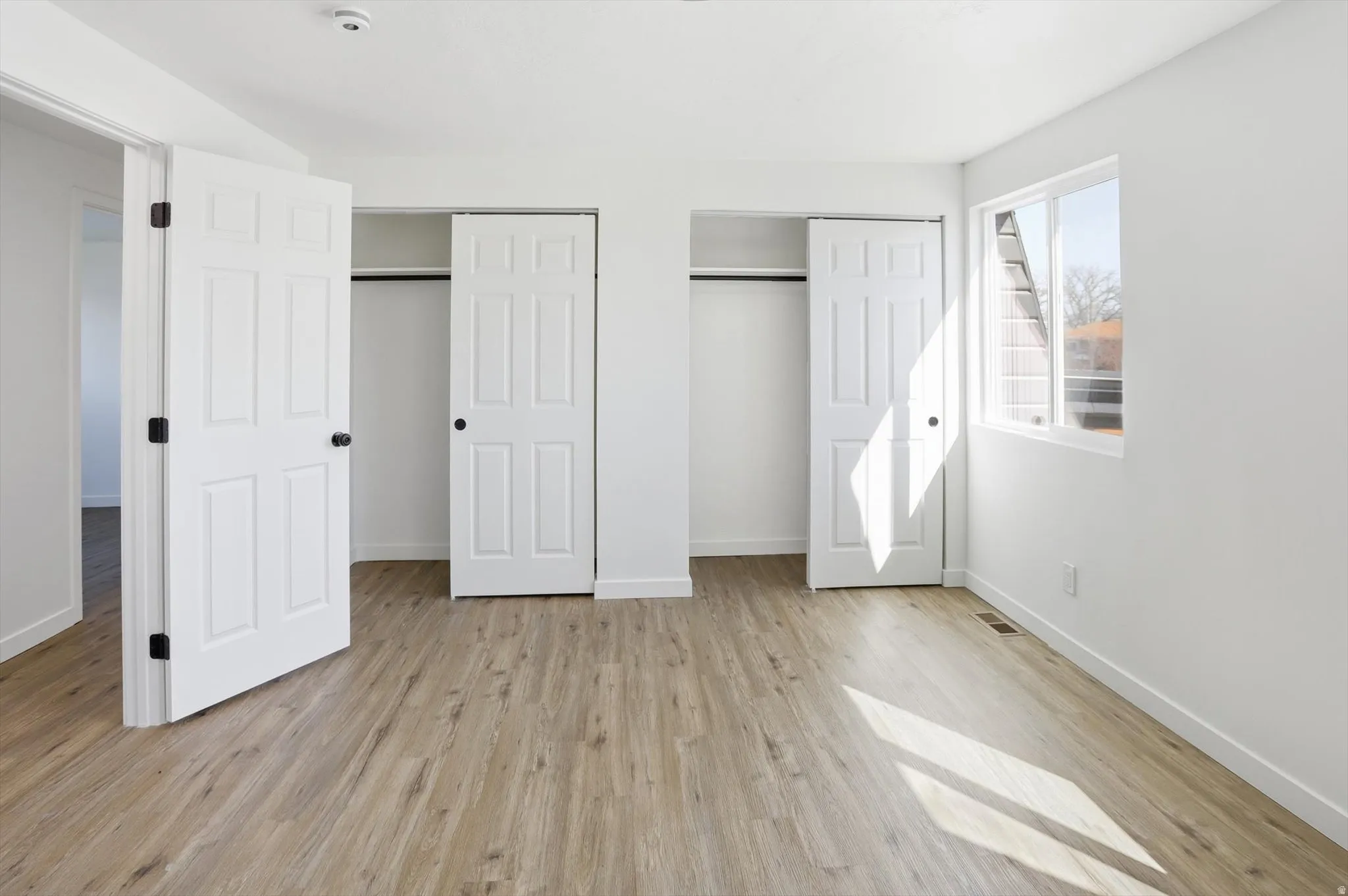 Unfurnished bedroom with multiple closets and light wood finished floors