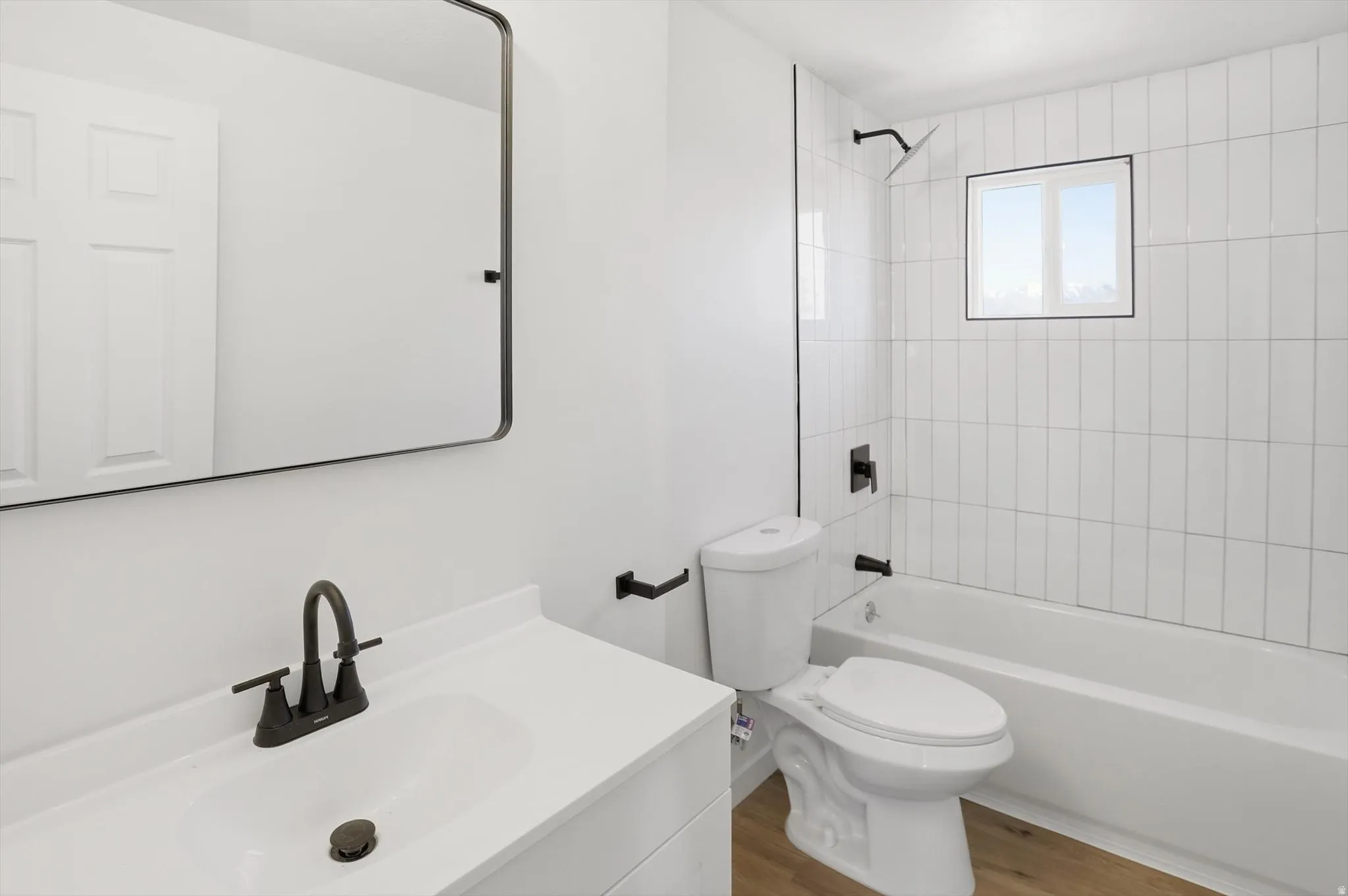 Bathroom featuring bathtub / shower combination, vanity, and wood finished floors