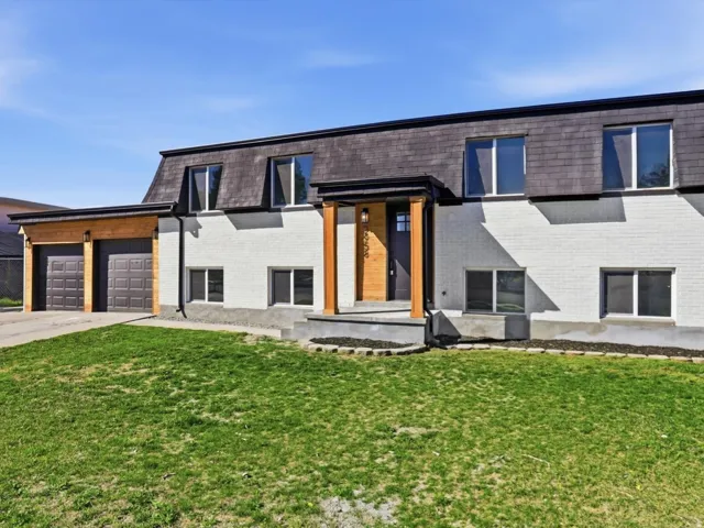 Contemporary home with driveway, mansard roof, and brick siding