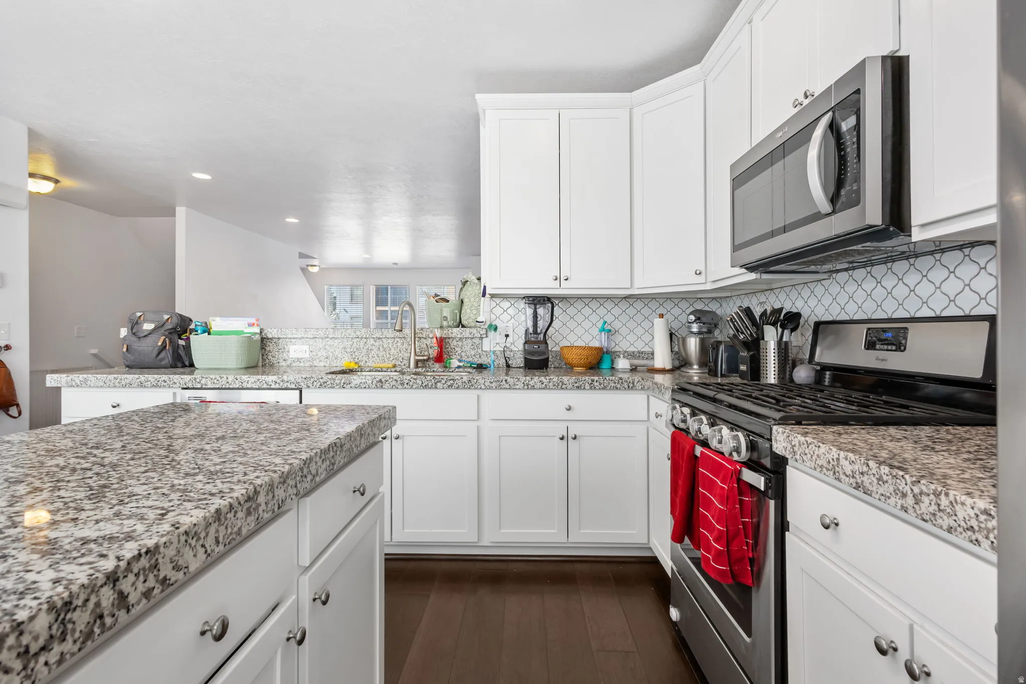Kitchen with stainless steel appliances, white cabinetry, dark wood-style flooring, a peninsula, and recessed lighting