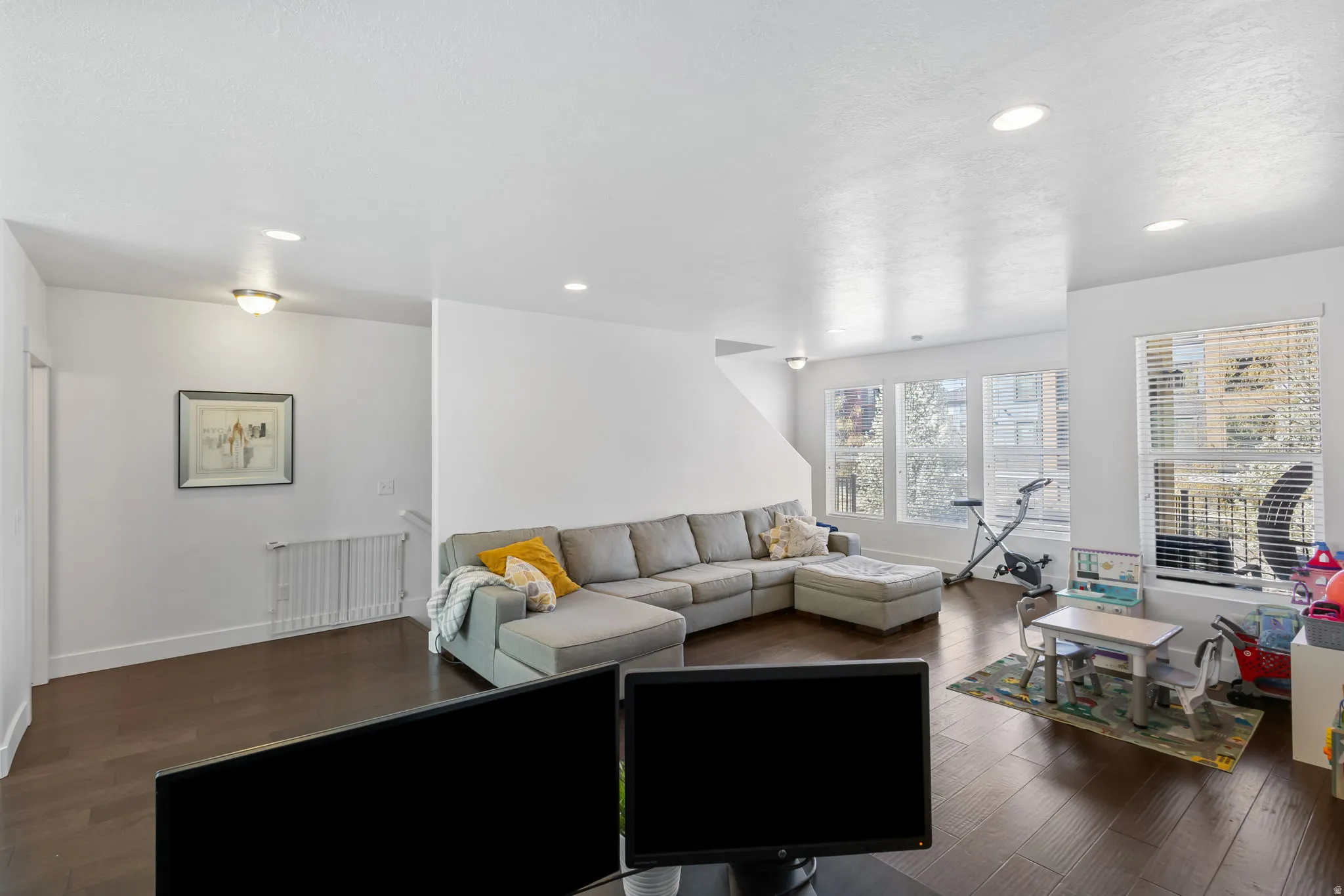 Living area featuring radiator, dark wood-type flooring, and recessed lighting