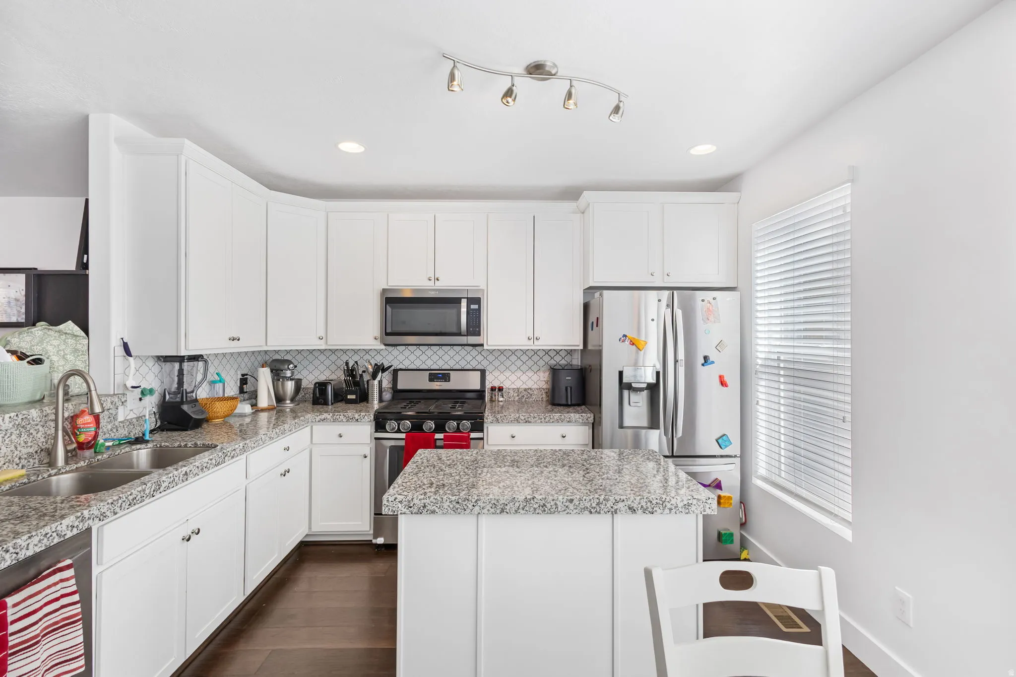 Kitchen with white cabinets, stainless steel appliances, dark wood-type flooring, a center island, and recessed lighting