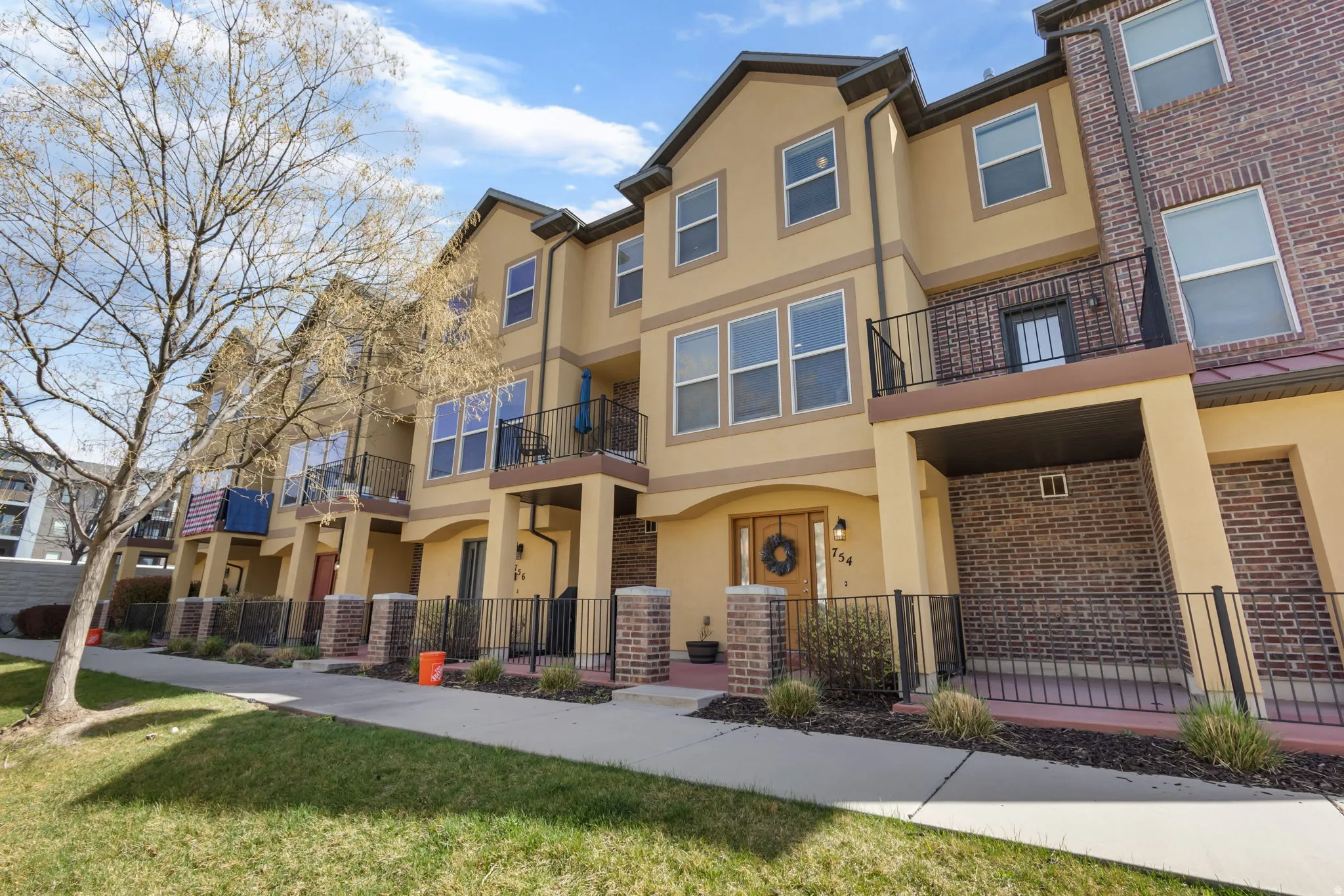 View of front facade with stucco siding, a balcony, and brick siding