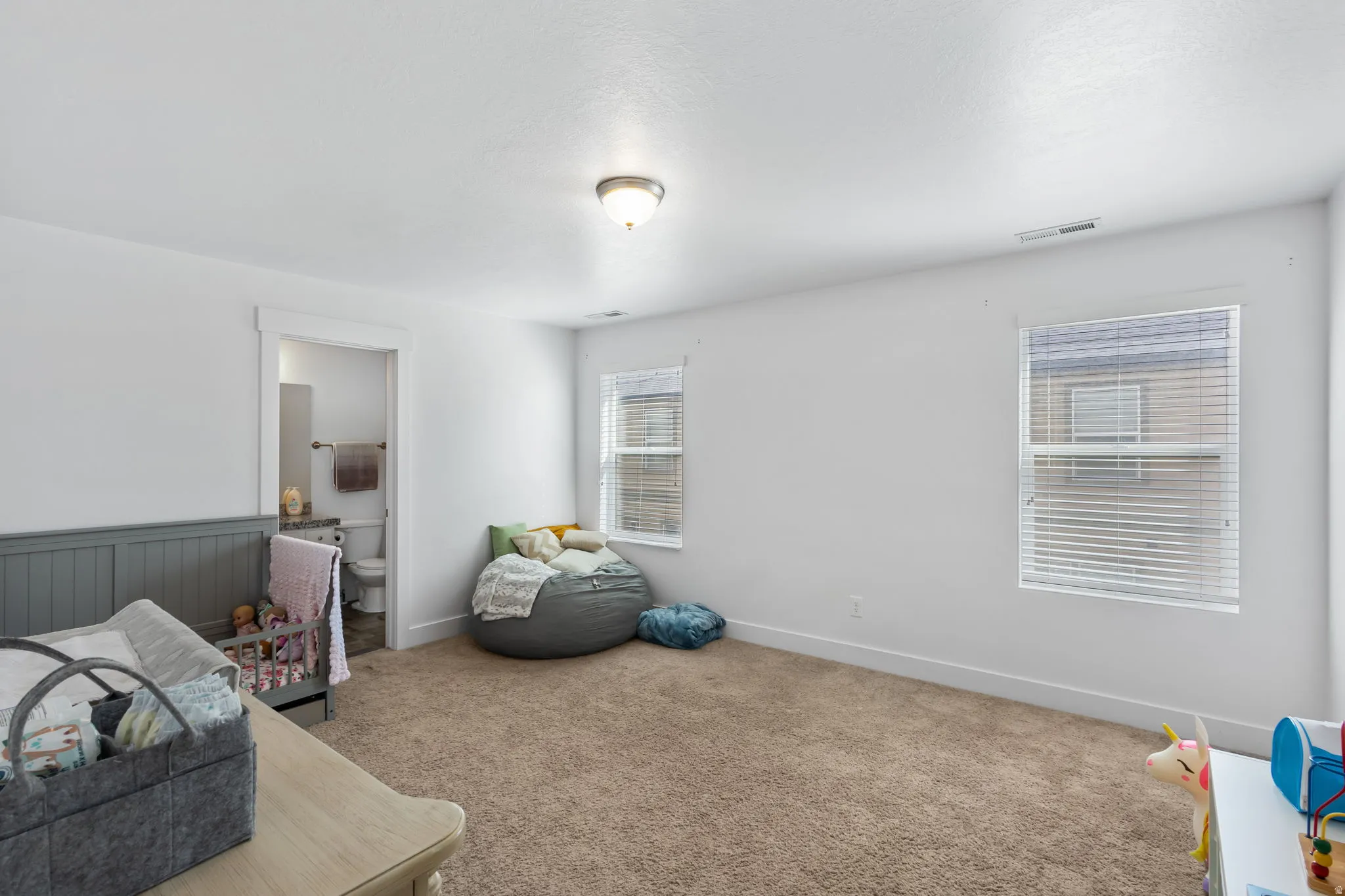Carpeted bedroom with ensuite bathroom and wainscoting