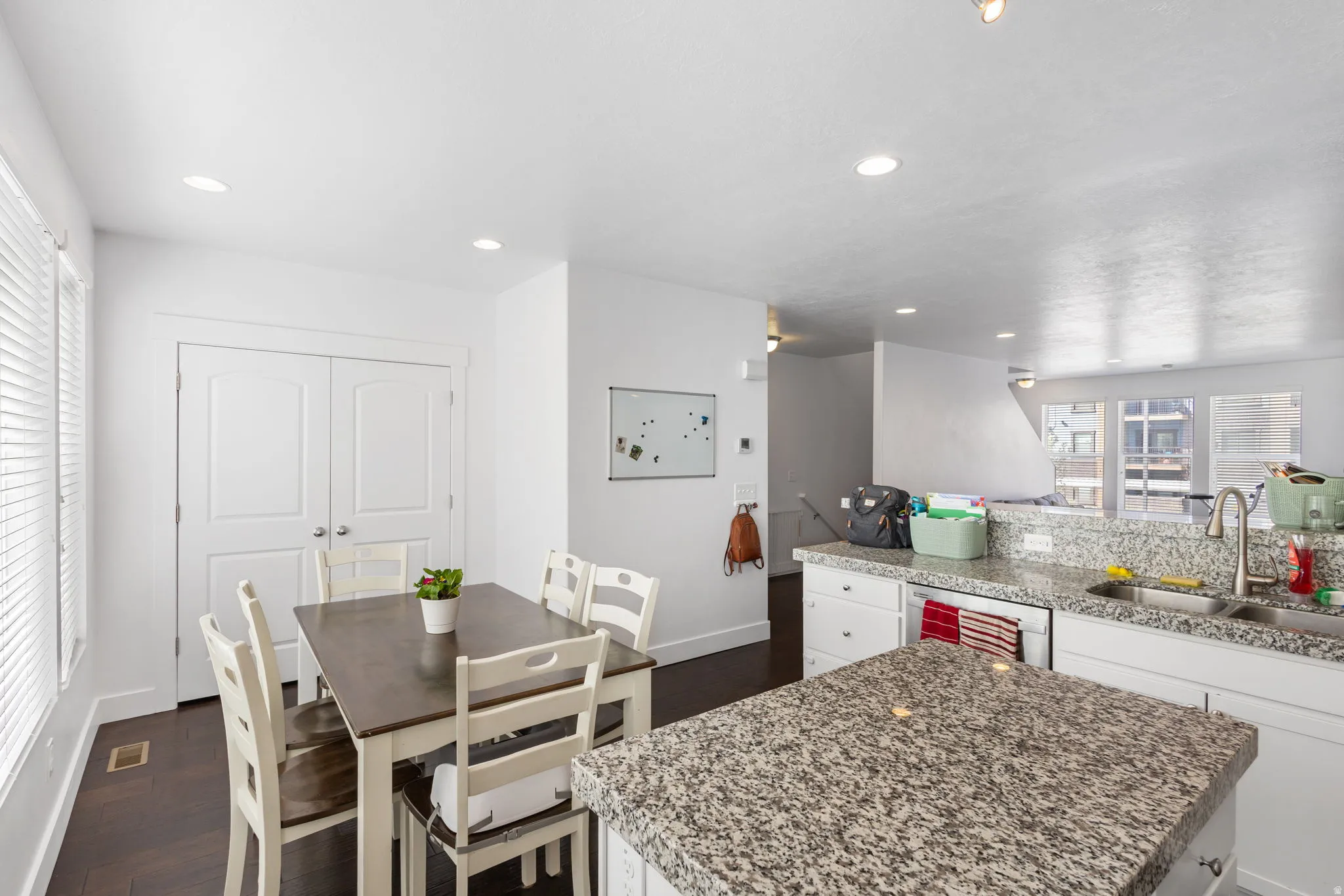 Kitchen featuring white cabinetry, dark wood-style floors, a kitchen island, recessed lighting, and stainless steel dishwasher