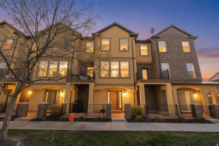 View of front of property featuring a balcony, brick siding, and stucco siding