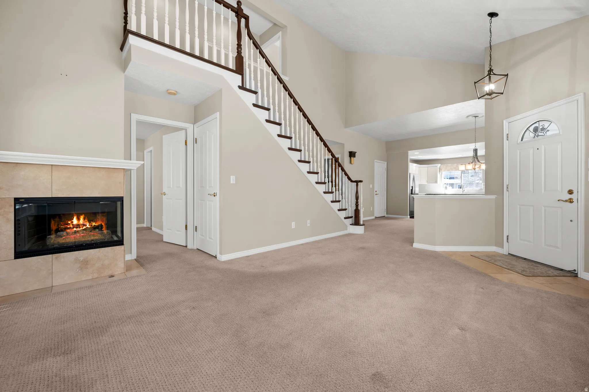 Entrance foyer featuring light carpet, a tile fireplace, lofted ceiling, and hanging lights