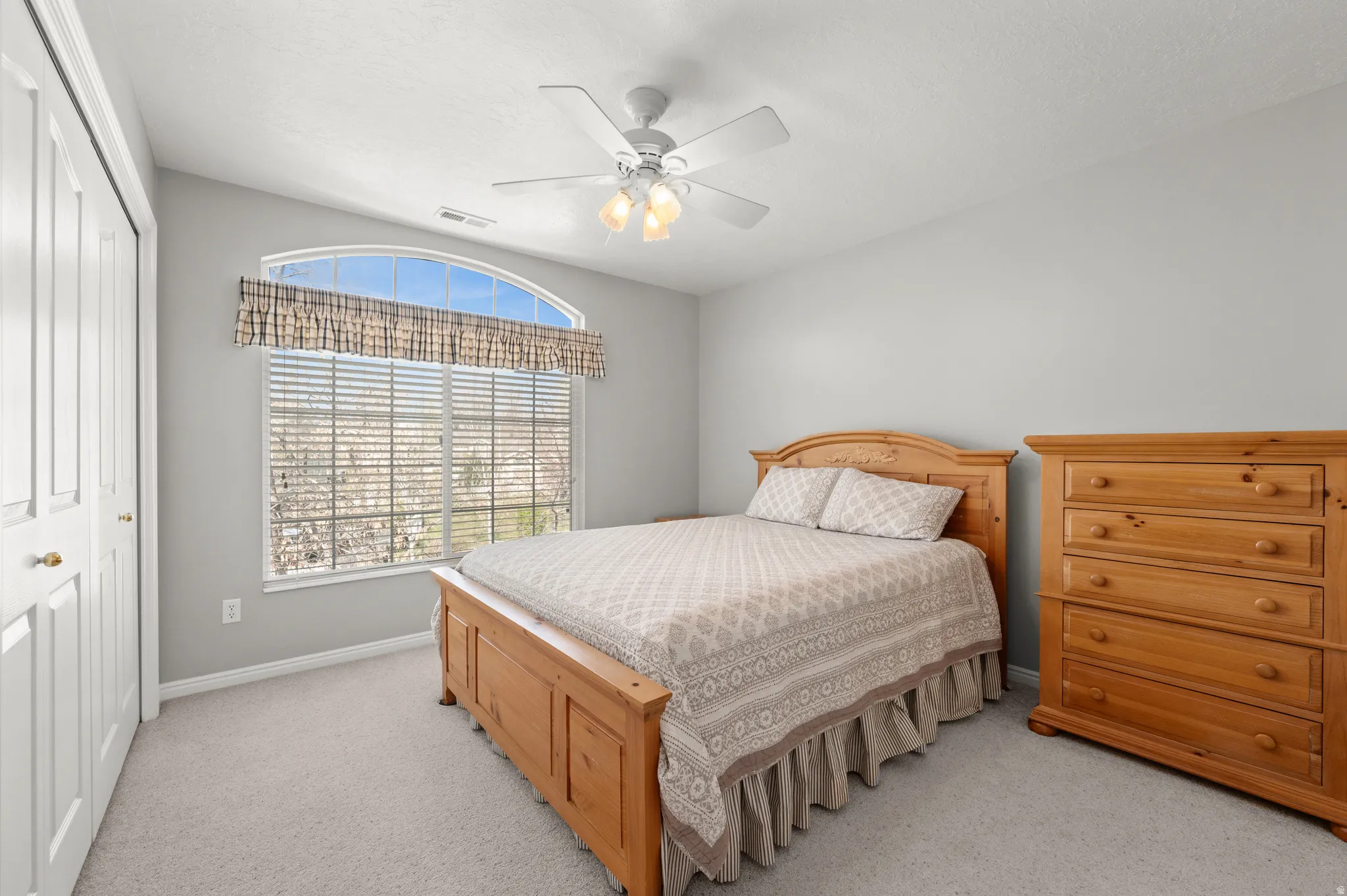 Bedroom with a closet, a ceiling fan, and light colored carpet