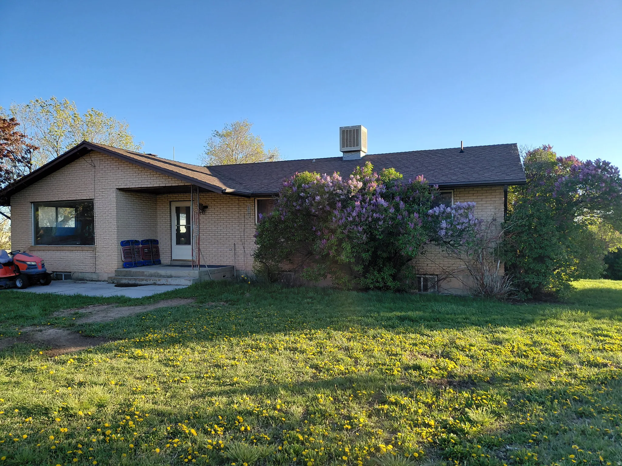 View of front of home featuring brick siding, a front yard, a shingled roof, and a patio area