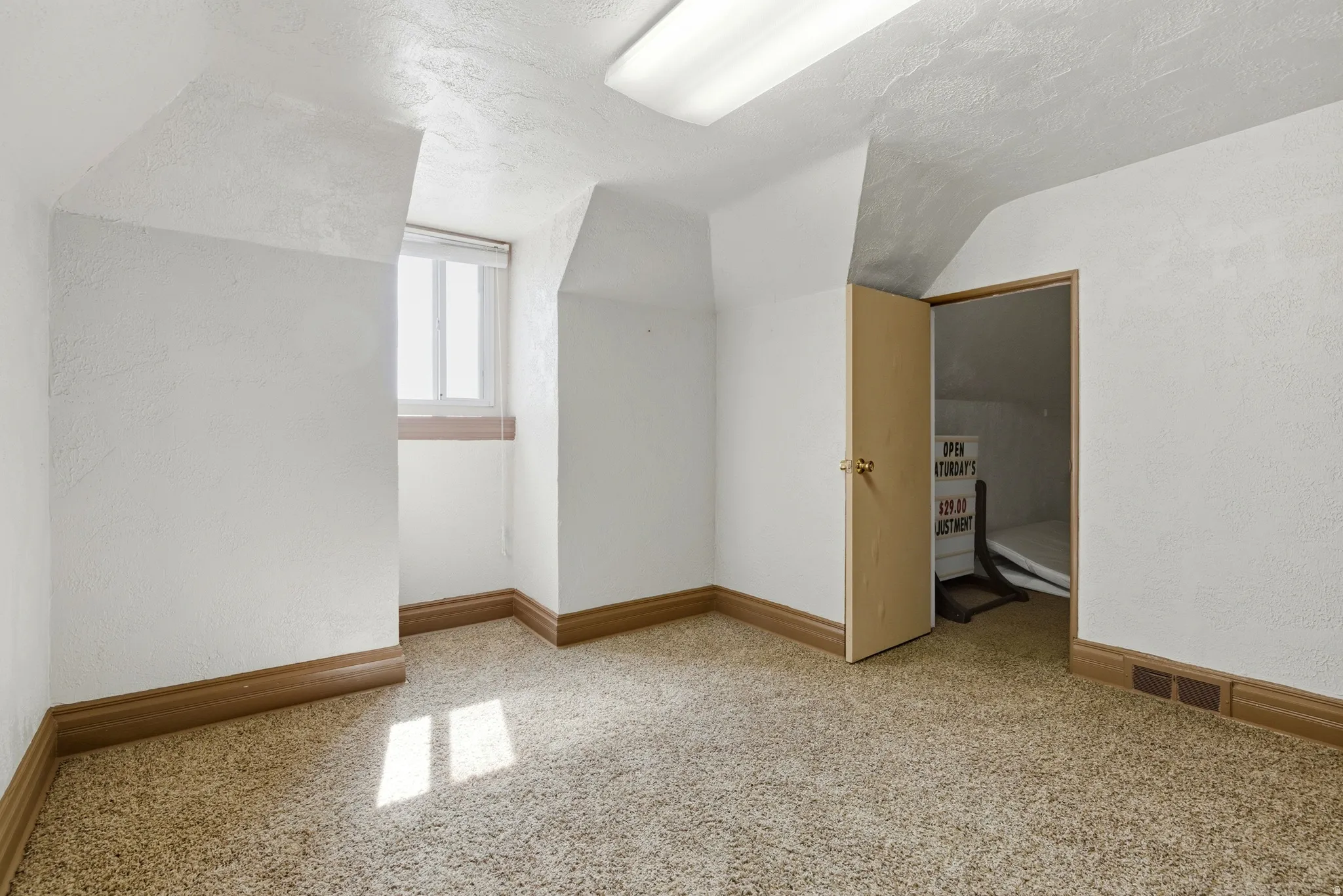 Additional living space featuring light carpet and a textured wall