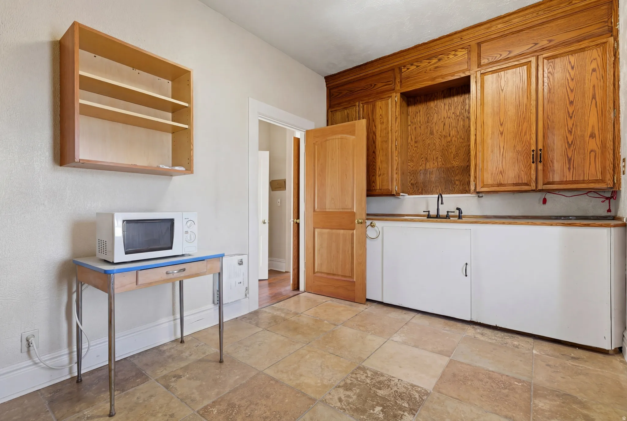 Kitchen featuring white microwave, open shelves, and wood finish cabinets