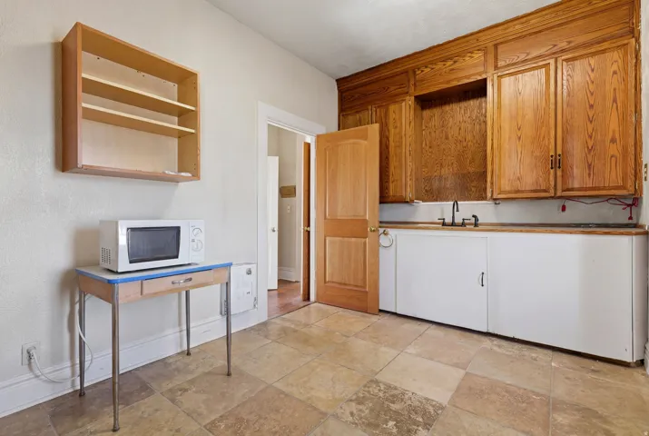 Kitchen featuring white microwave, open shelves, and wood finish cabinets