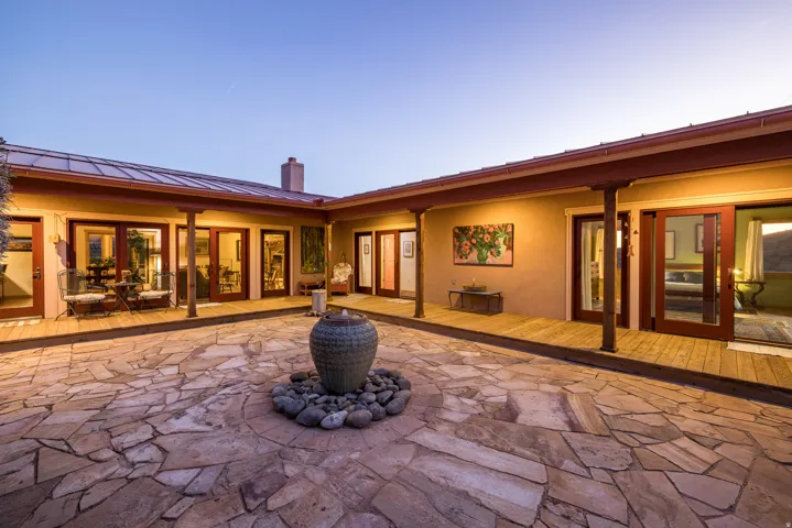 Rear view of house with a chimney, stucco siding, a patio, a standing seam roof, and a wooden deck