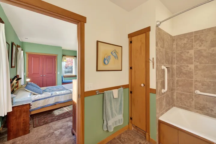 Full bathroom featuring bathing tub / shower combination, ensuite bathroom, and dark tile patterned flooring