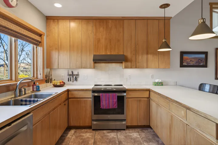 Kitchen with stainless steel appliances, light countertops, decorative backsplash, pendant lighting, and a peninsula