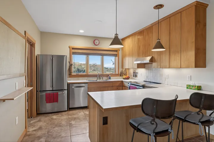 Kitchen with light countertops, a breakfast bar, a peninsula, stainless steel appliances, and tasteful backsplash