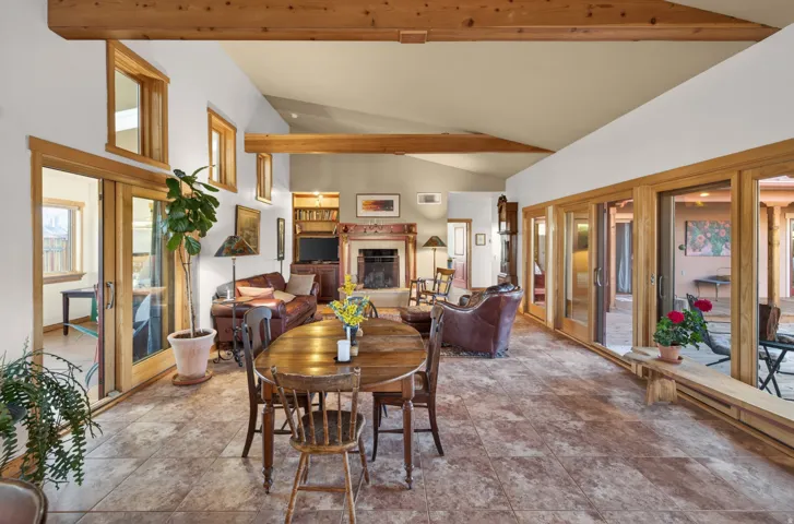 Dining room with a fireplace with raised hearth, vaulted ceiling, and french doors