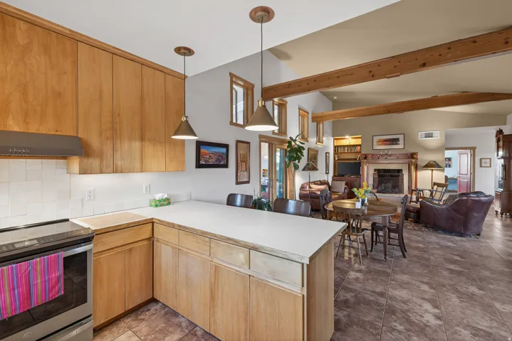 Kitchen with stainless steel range with electric stovetop, a peninsula, light countertops, open floor plan, and decorative light fixtures