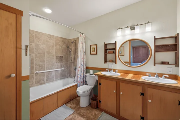 Bathroom with double vanity, shower / bathtub combination with curtain, and light tile patterned flooring
