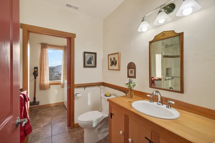 Full bath featuring vanity, dark tile patterned flooring, and a shower with shower door