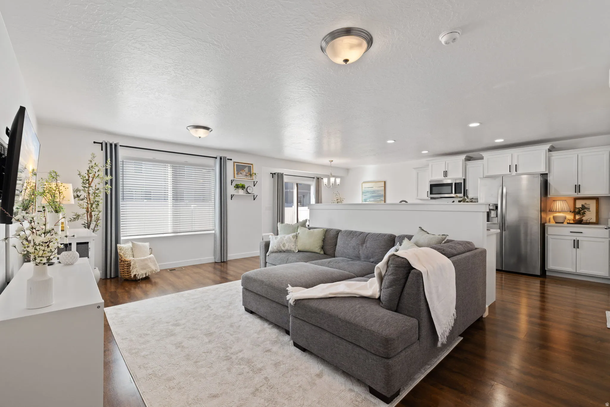 Living area with dark wood-style flooring, plenty of natural light, a textured ceiling, and a chandelier