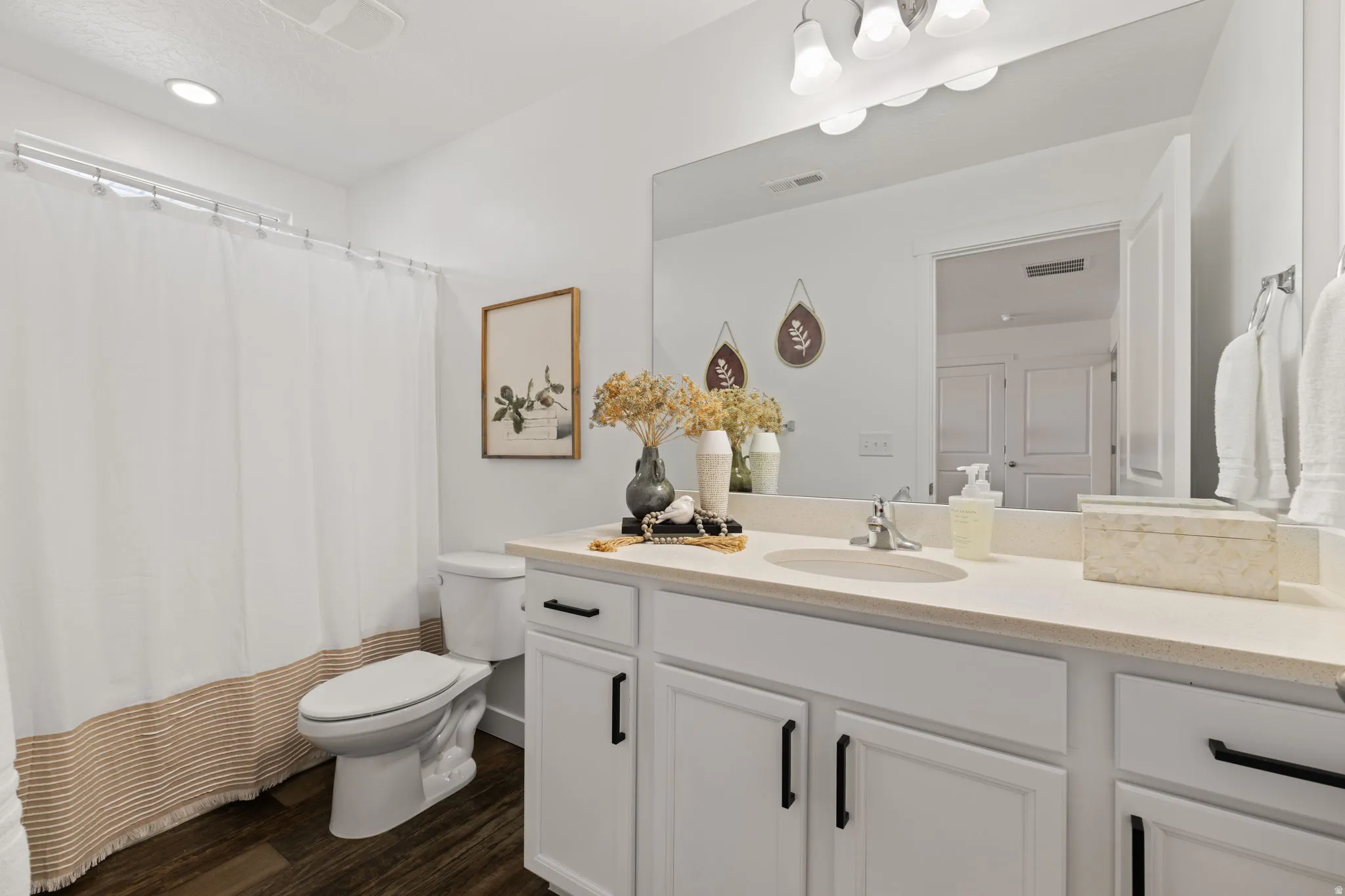 Full bathroom with vanity, curtained shower, and dark wood finished floors