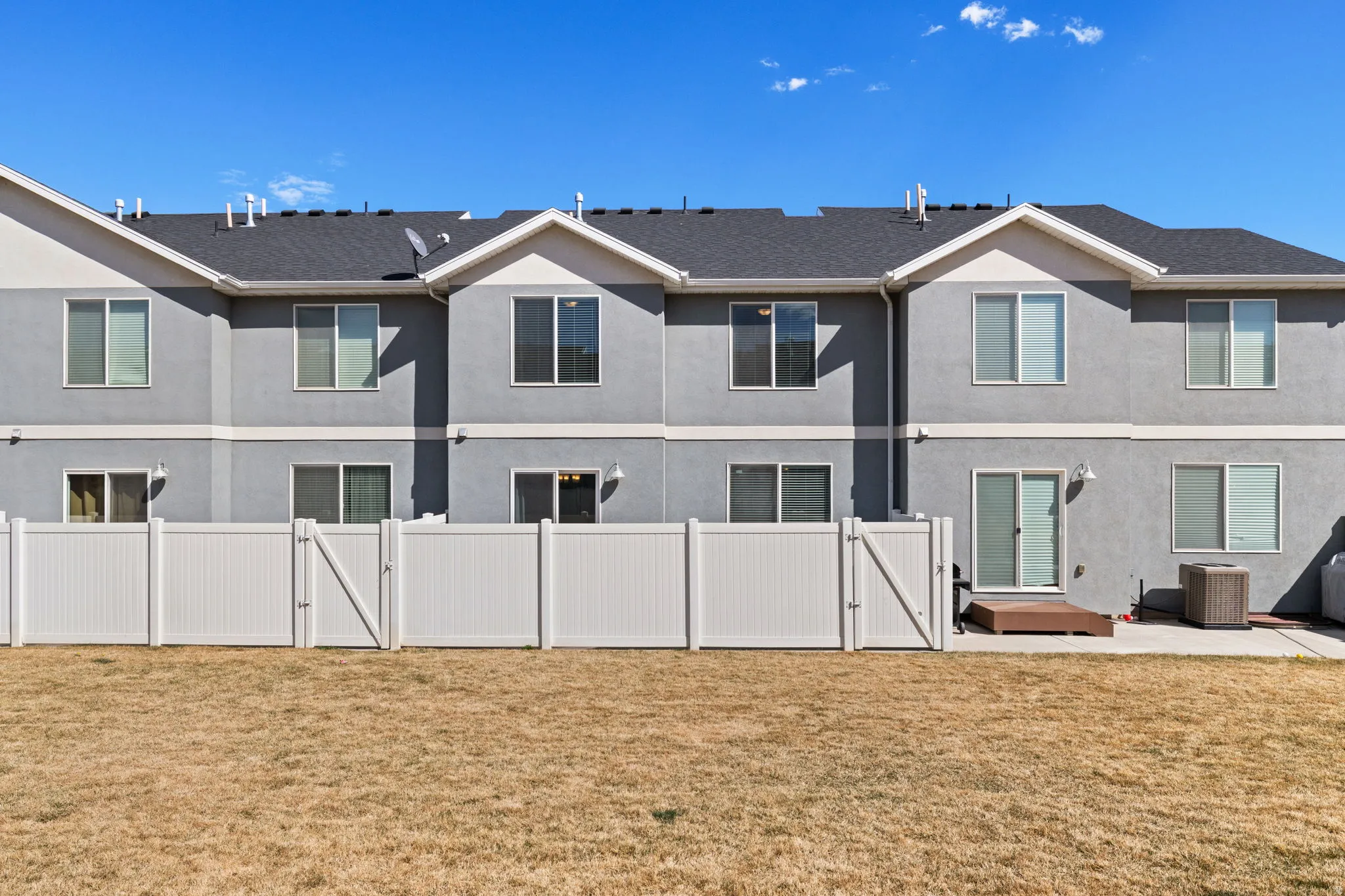 Back of house with a gate, a patio, and stucco siding