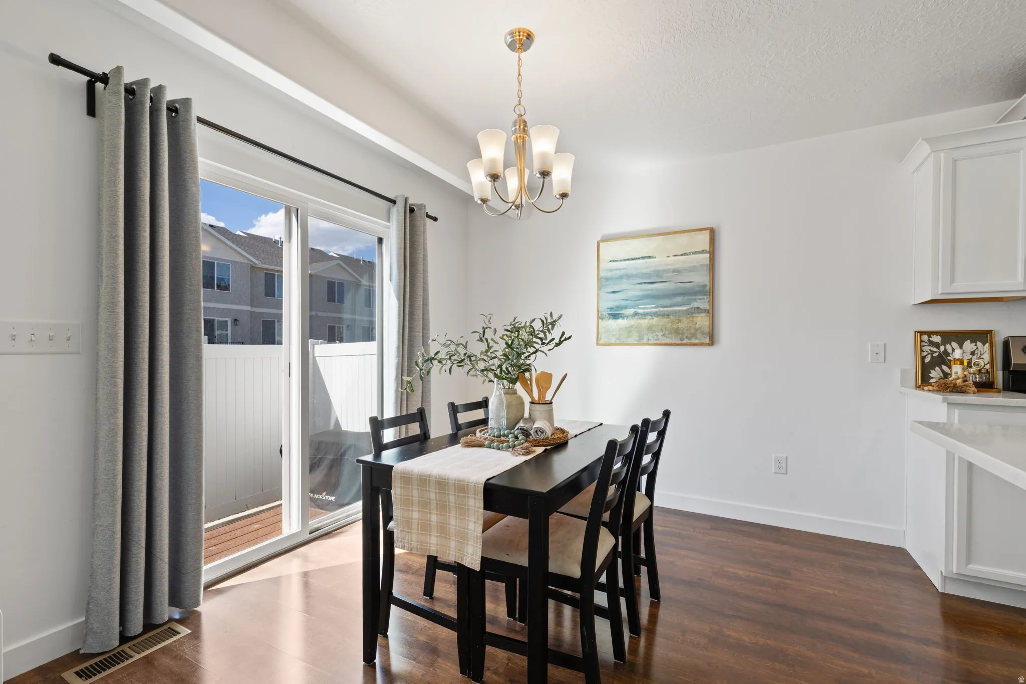 Dining area featuring suspended lighting and dark wood-style flooring