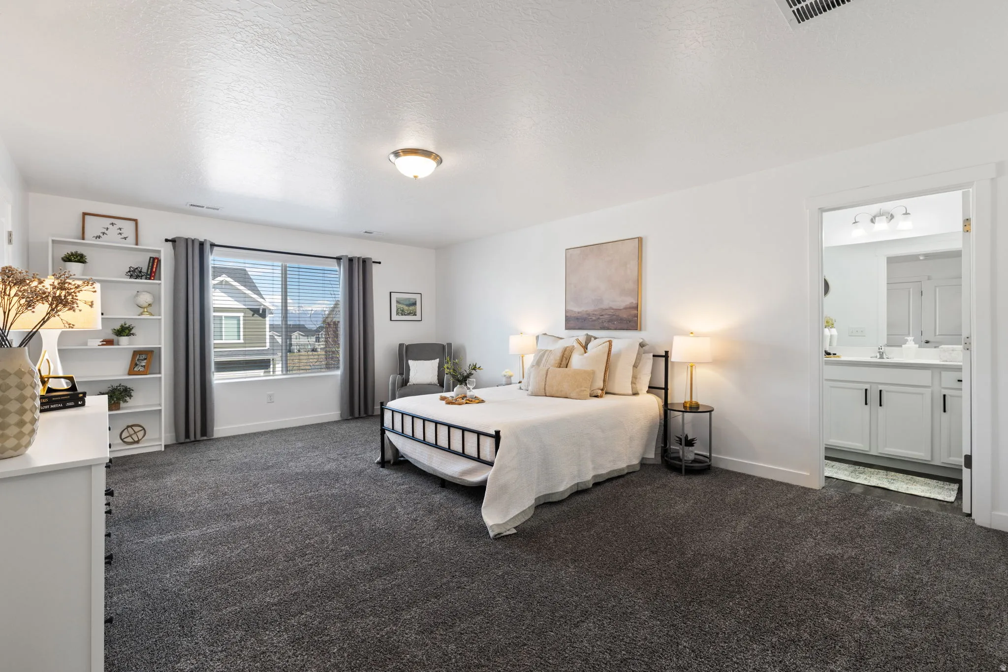 Bedroom featuring dark colored carpet, a textured ceiling, and ensuite bath