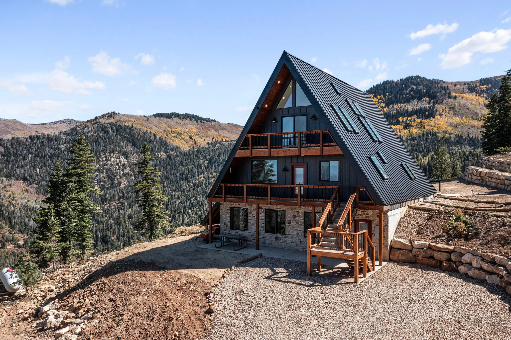Back of property with a mountain view, a patio area, and stone siding