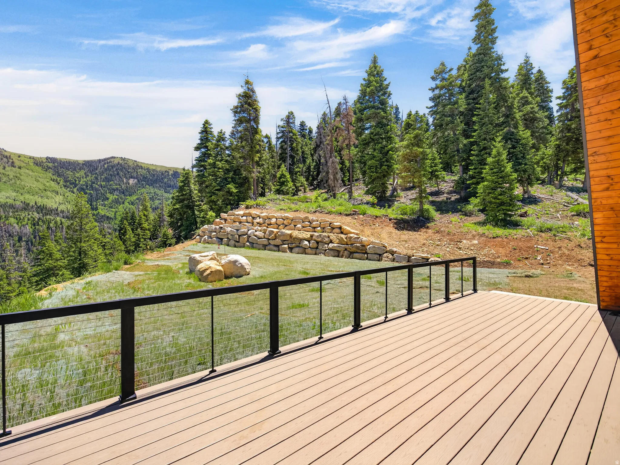 Expansive wood-finish deck with a black metal and cable railing system