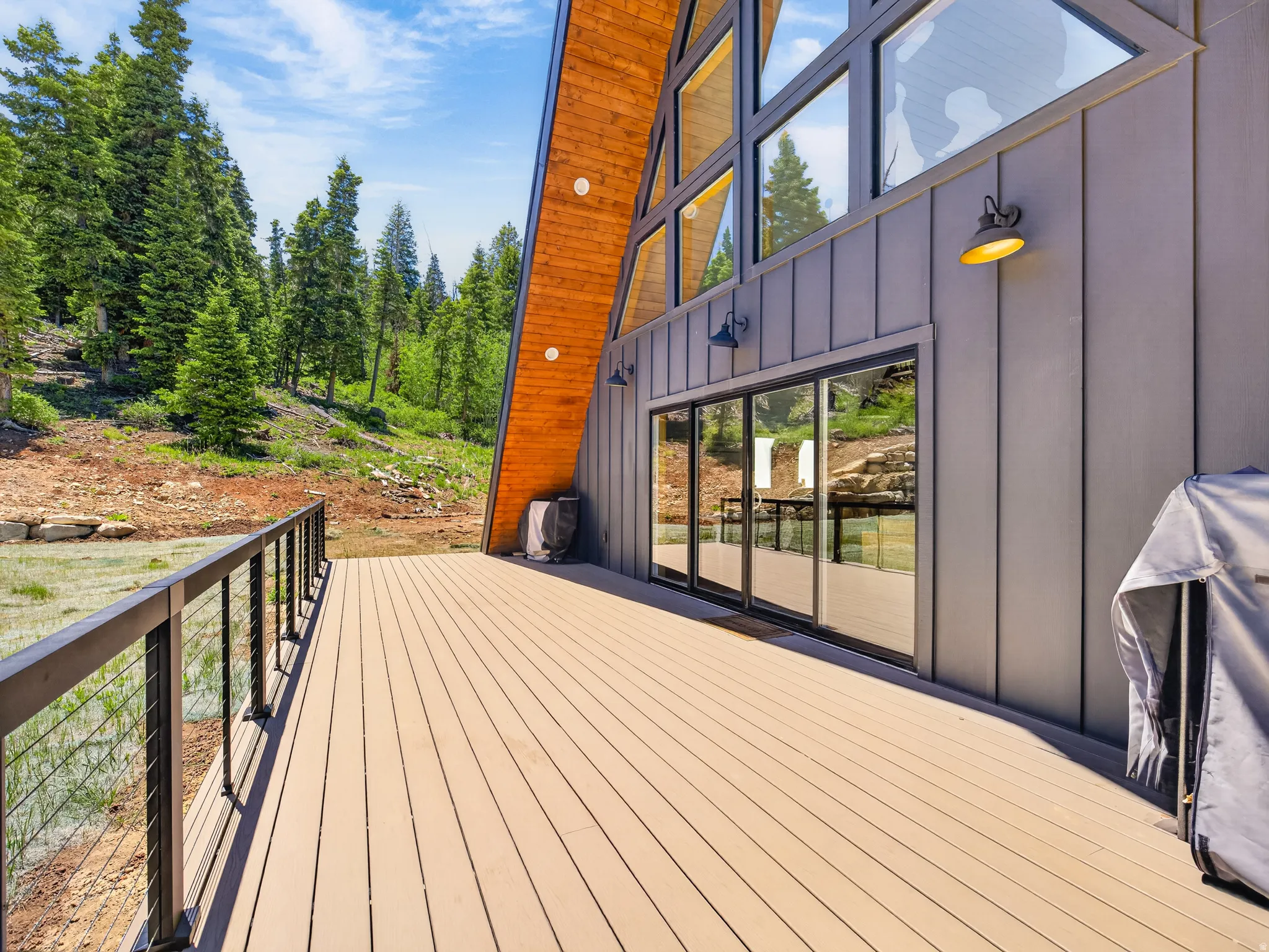 Spacious outdoor deck featuring light-toned composite decking with a black metal cable railing