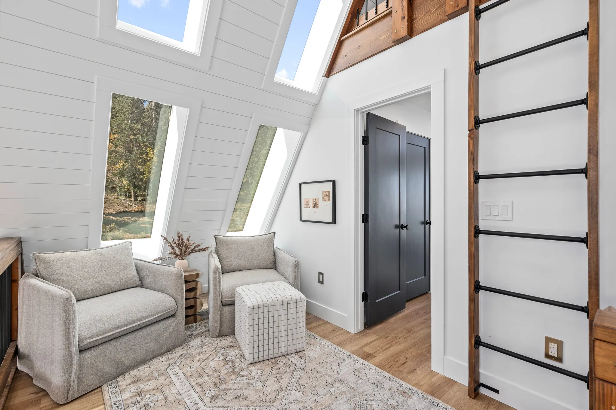 Sitting room featuring light wood-style floors, wood walls, and a high ceiling