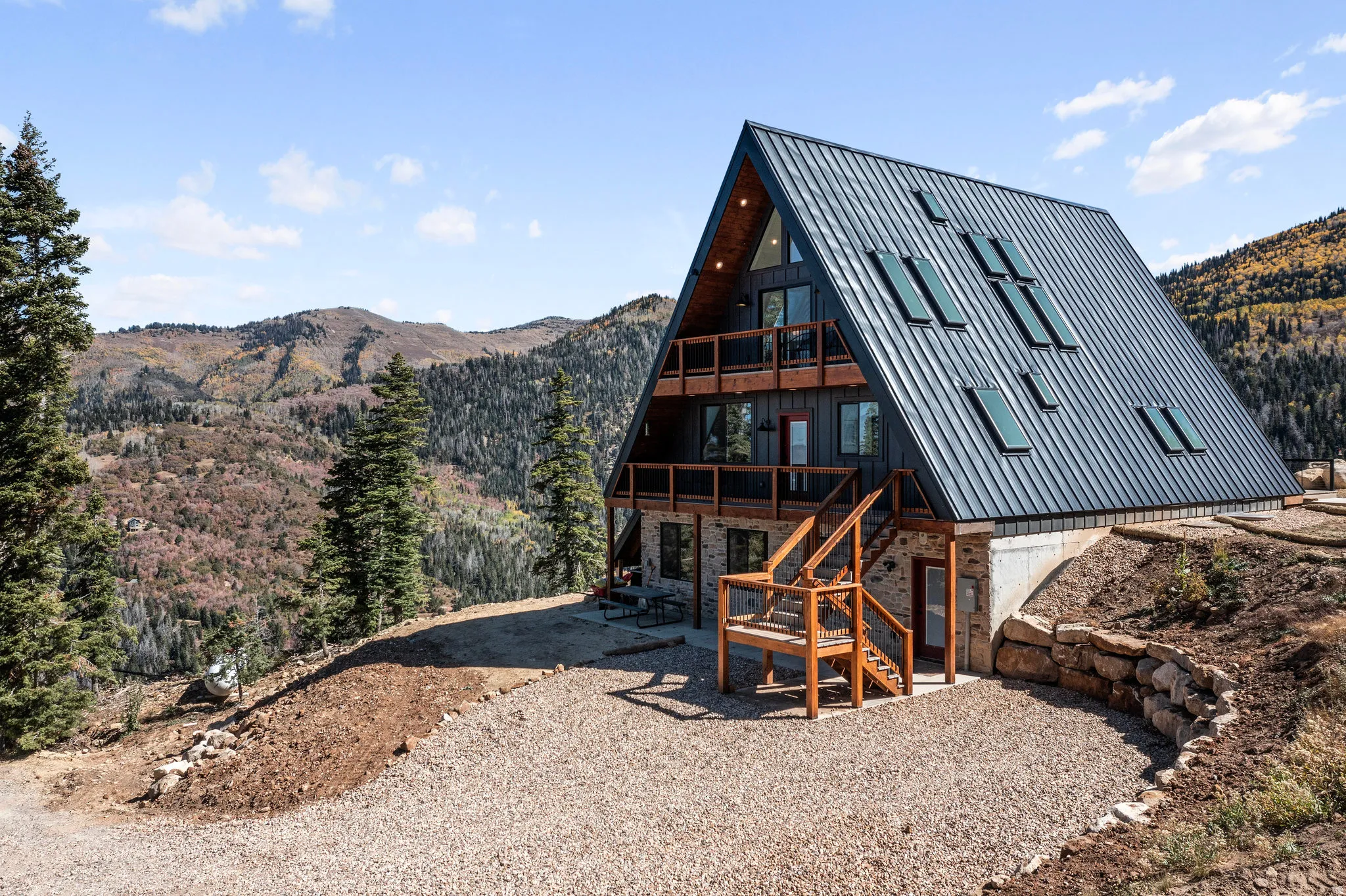 Back of property with a mountain view, stone siding, and a patio