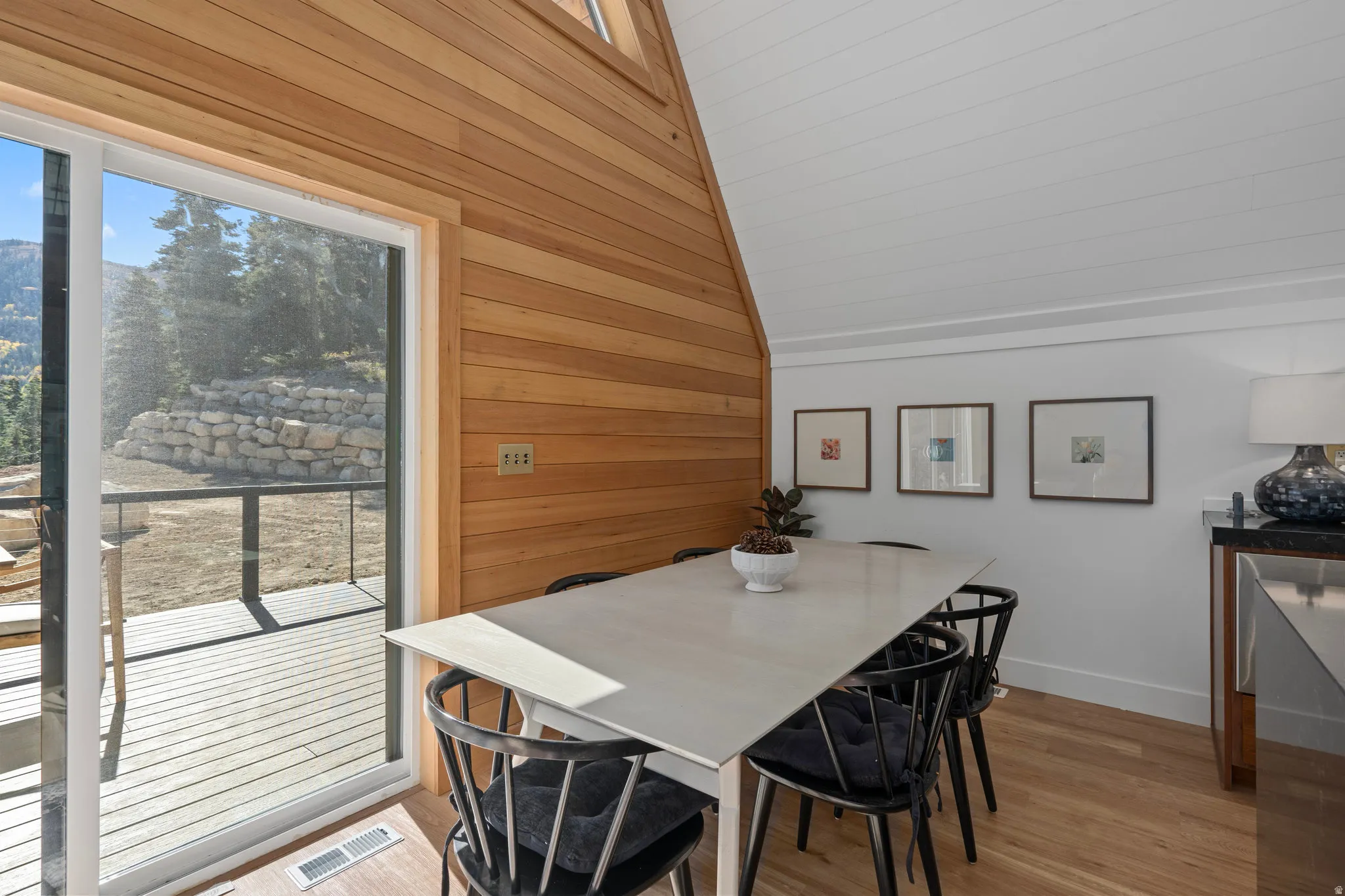 Dining space featuring wooden walls, light wood-type flooring, and vaulted ceiling