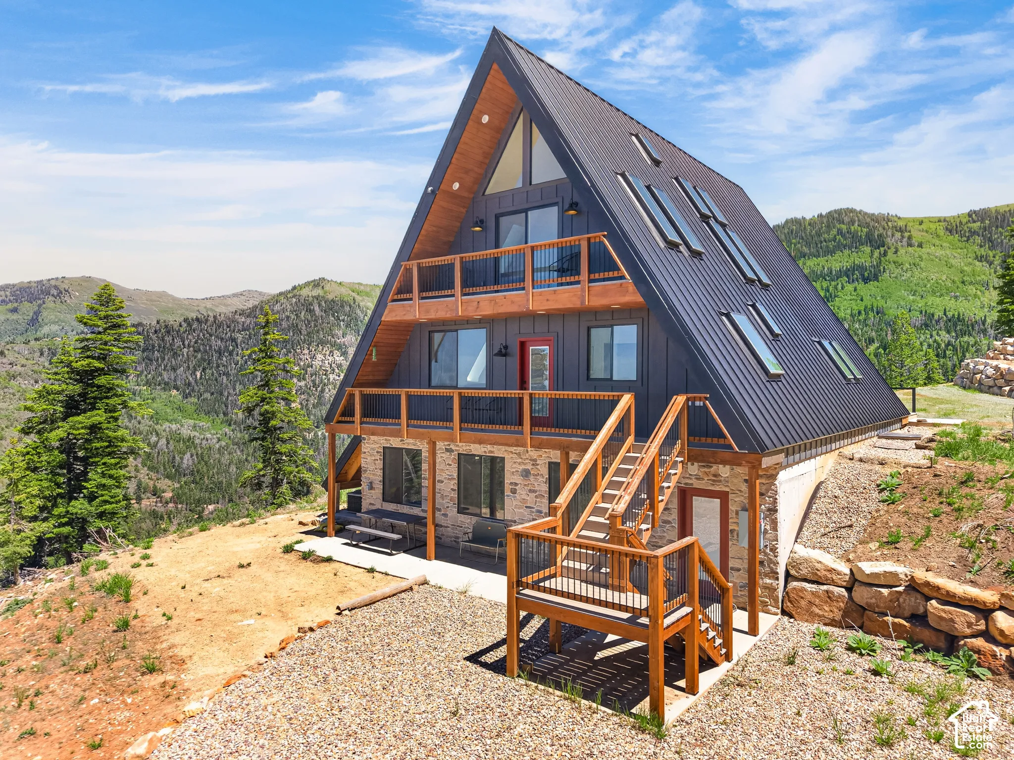 Striking A-frame architecture with a dark metal roof, multiple skylights, and wood-finish trim