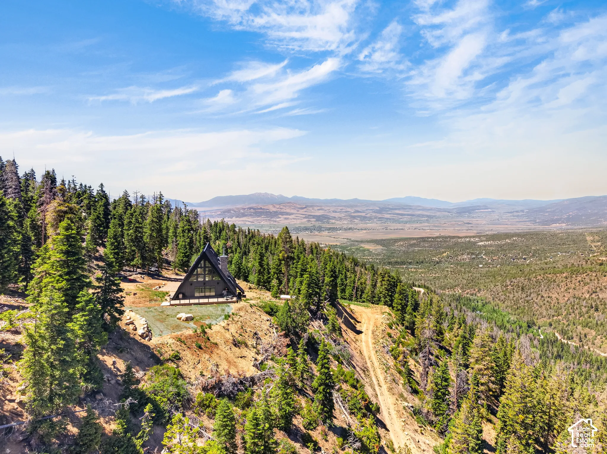 A-frame architectural style with expansive glazing, surrounded by mature evergreen trees